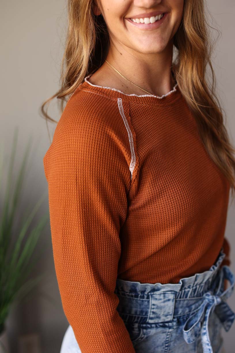 This Camel Textured Crewneck Long Sleeve Top is a chic fashion statement with a textured deep camel color. The feminine ivory hem line detail provides an elegant touch, plus the slightly shorter length makes it perfect for dressing up high rise styles.