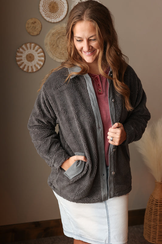 Woman wearing a gray fleece jacket in a room with decorative wall art.