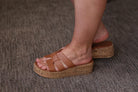 Brown cork sandals worn on a textured surface
