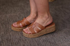 Brown sandals with cork platforms worn by a person on a textured surface
