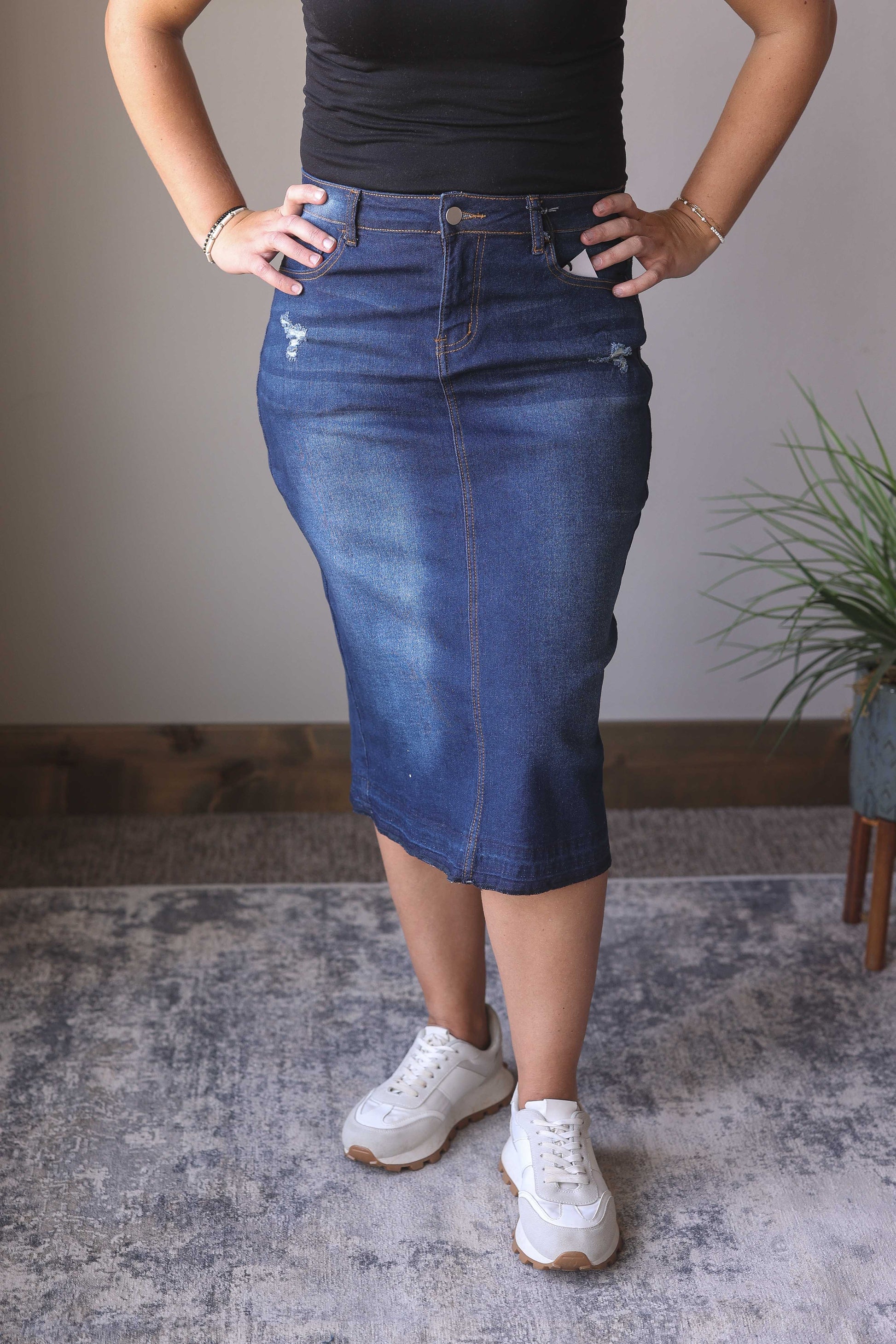 Introducing the Emily Dark Wash Back Slit Denim Skirt! This stylish midi skirt is perfect for the holiday season, featuring a dark wash, stretchy fabric, back slit, and minimal distressing for a dressier look. Pair it with your favorite holiday outfits for a fabulous and comfortable look. Hard to find Modest Denim Skirts for Women at Classy Closet Boutique!