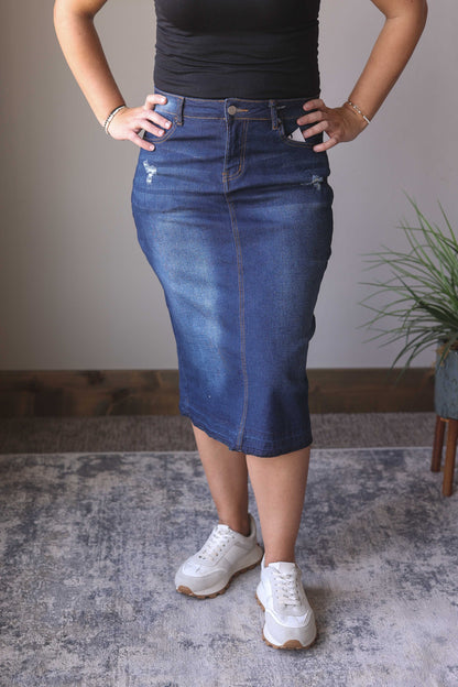 Introducing the Emily Dark Wash Back Slit Denim Skirt! This stylish midi skirt is perfect for the holiday season, featuring a dark wash, stretchy fabric, back slit, and minimal distressing for a dressier look. Pair it with your favorite holiday outfits for a fabulous and comfortable look. Hard to find Modest Denim Skirts for Women at Classy Closet Boutique!