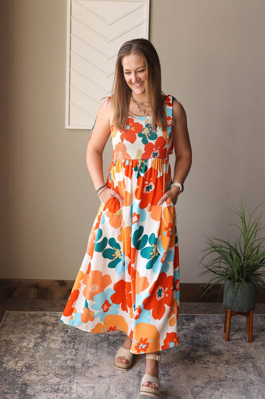 This summer, spread happiness and cheer with our airy and flowy Self-Tie Smocked Maxi Dress. Perfect for any occasion, whether it's a day at the beach or a dressy event. The self-tie straps and smocked bust add a touch of elegance, while pockets offer practicality. Bring on the sunshine vibes with our cheerful floral dress styled alone or layered under a white or blue denim jacket! Classy Closet Online Boutique Hull Iowa