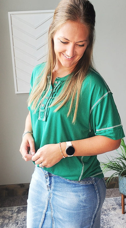 This cute Kelly Green Henley Top features a relaxed fit and pretty white contrast stitching. Perfect for everyday mom life, it's effortless and comfortable to wear, making it a go-to choice for any casual occasion. Easy to style and versatile, this top is a must-have addition to your wardrobe. Classy Closet Modest Boutique Clothing for Everyday Casual Outfits