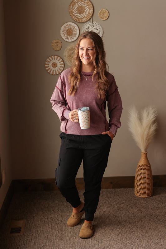 Woman wearing Burgundy Mineral Wash Side Slit Sweatshirt with relaxed fit, styled casually with joggers, perfect for comfortable everyday wear for spring style