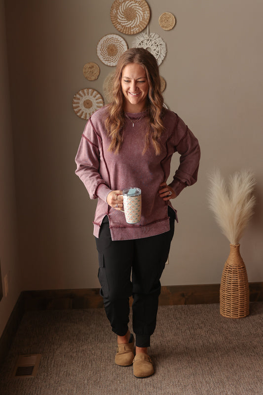 Woman wearing Burgundy Mineral Wash Side Slit Sweatshirt with relaxed fit, styled casually with joggers, perfect for comfortable everyday wear