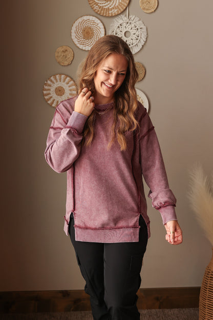 Woman wearing Burgundy Mineral Wash Side Slit Sweatshirt with relaxed fit, styled casually with joggers, perfect for comfortable everyday wear