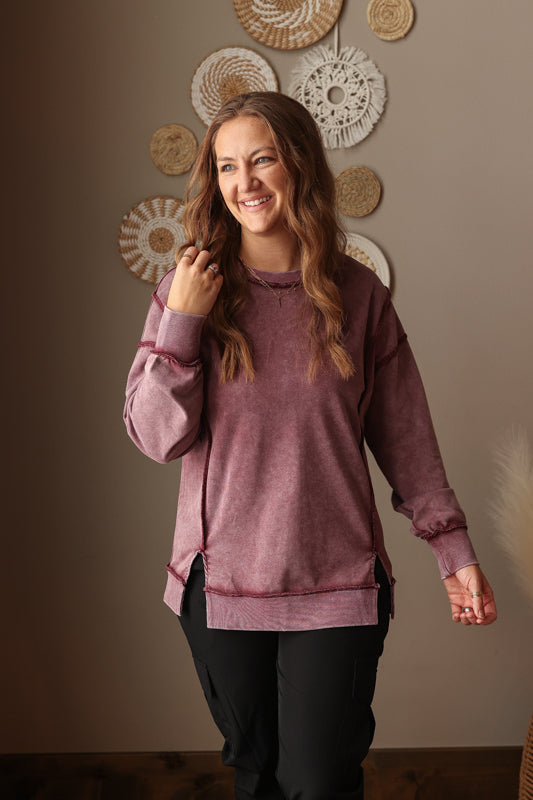 Woman wearing Burgundy Mineral Wash Side Slit Sweatshirt with relaxed fit, styled casually with joggers, perfect for comfortable everyday wear