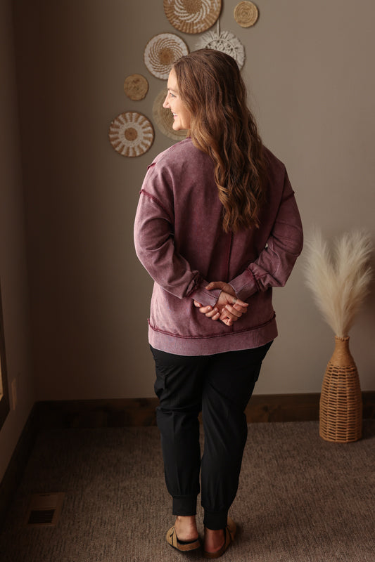 Woman wearing Burgundy Mineral Wash Side Slit Sweatshirt with relaxed fit, styled casually with joggers, perfect for comfortable everyday wear for winter spring transition outfit
