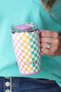 Woman in turquoise shirt and denim skirt holding a polka dot mug in a room with decorative wall art.