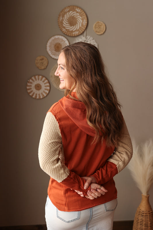 Woman wearing an orange vest standing against a wall with decorative plates.