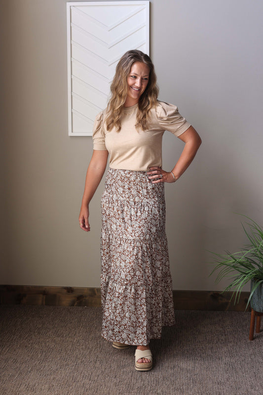 This brown floral ruffled maxi skirt combines a cute neutral boho vibe with a slicker material for a fresh look. Featuring an elastic waistband and a flattering length, it’s comfortable and easy to wear. Pair it with white, tan, or a denim jacket to create multiple stylish outfits perfect for any occasion.