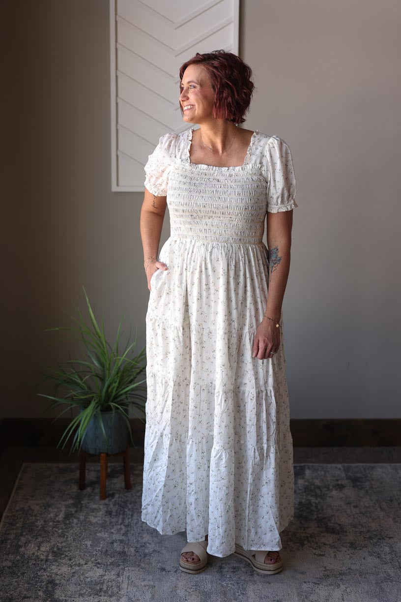 Get ready to feel feminine and chic in our stunning White Floral Smocked Tiered Maxi Dress! With its smocked check, puff short sleeves, and hidden pockets, this dress effortlessly combines style and comfort. The white fabric with little floral green sprigs brings a touch of elegance to this must-have piece. Classy Closet online women's boutique for Easter dresses, maxi dress, wedding outfits, church outfits, and modest fashion. hull iowa