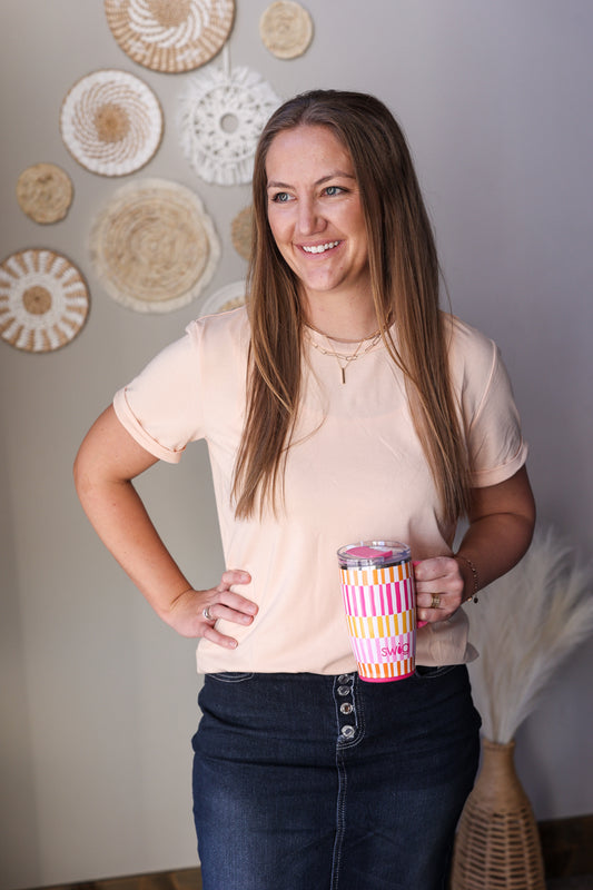 Woman holding a colorful tumbler in a room with decorative wall art.