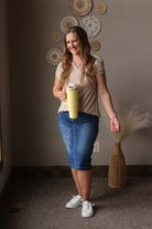 Woman holding a yellow water bottle in a room with decorative wall art and a vase.