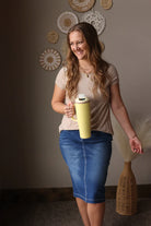 Woman holding a yellow thermos against a wall with decorative plates.