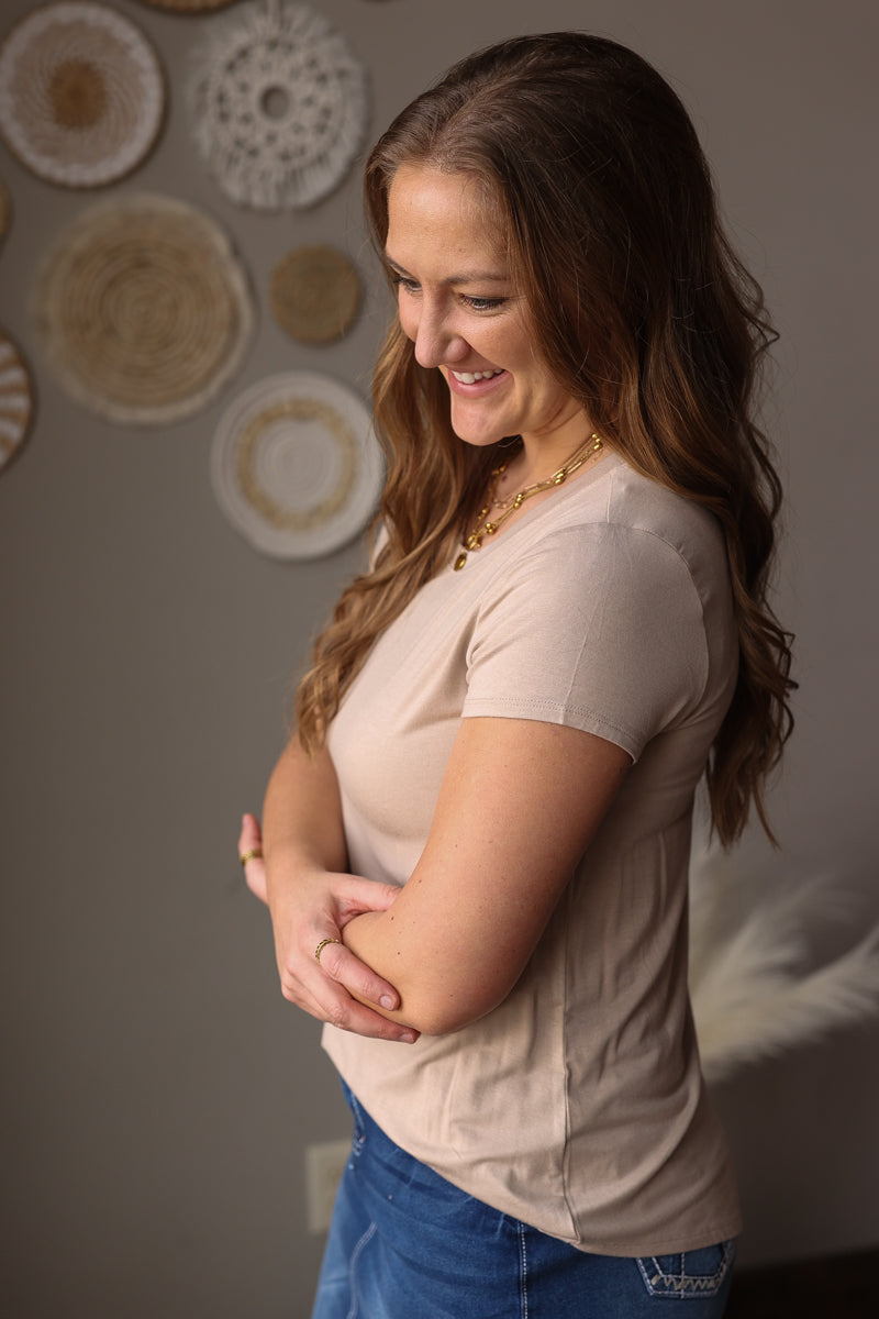 Woman standing with arms crossed against a neutral wall with decorative plates.