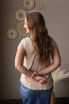 Woman standing with arms crossed in a room with decorative wall art.