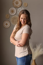 Woman standing with arms crossed against a wall with decorative plates.