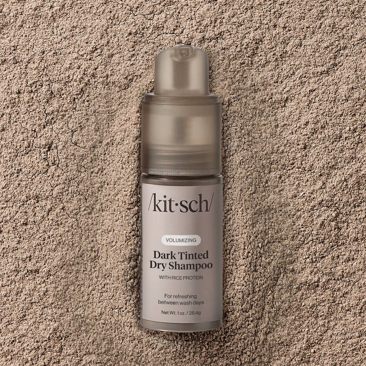 Kit-sch dark tinted dry shampoo bottle on a textured beige surface