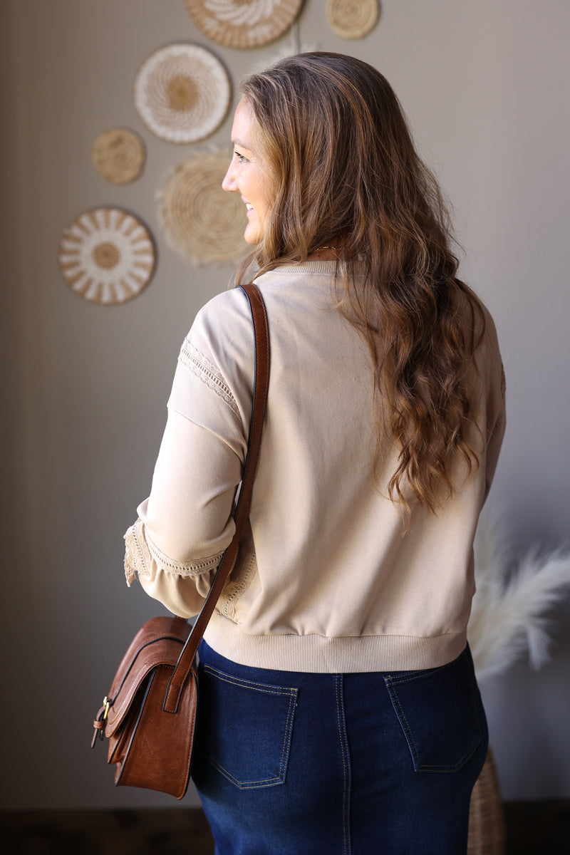 Angled back view of a parchment sweatshirt showing the solid back and lace-trimmed long sleeves.