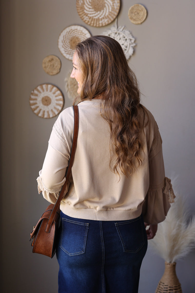 Rear side view of a parchment sweatshirt showing the sleeve lace detail and gathered hem.