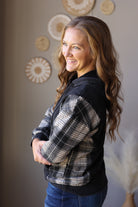 Side view of a black hoodie highlighting the grey plaid sleeve and solid black body.