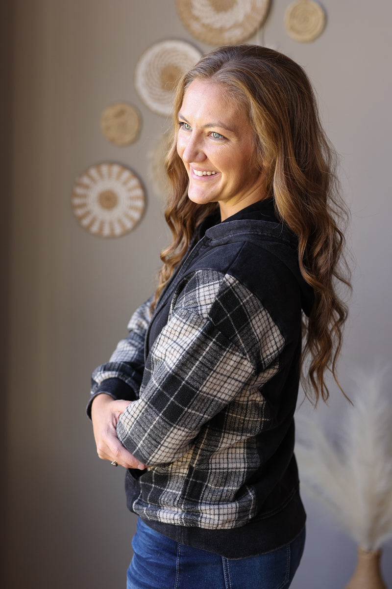 Side view of a black hoodie highlighting the grey plaid sleeve and solid black body.