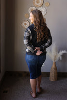 Full outfit view of a black plaid sleeve hoodie with a dark denim midi skirt and brown boots.