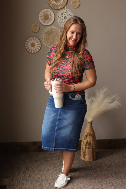 Woman holding a cup in a room with decorative wall hangings and a vase.
