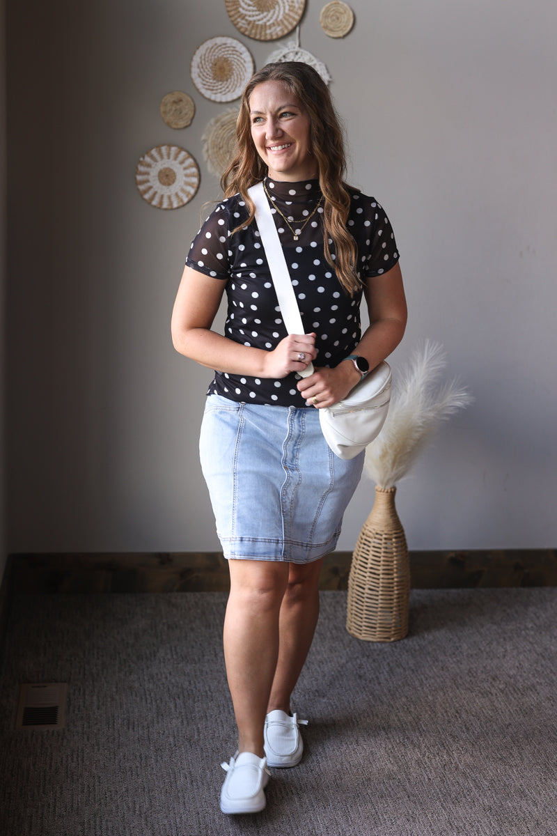 Woman holding a white bag indoors with decorative wall art in the background