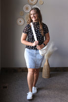 Woman holding a white bag indoors with decorative wall art in the background