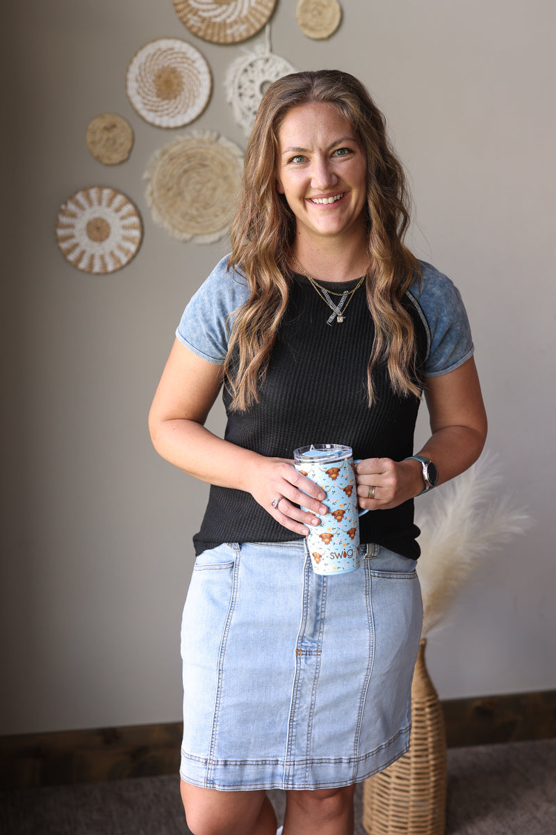 Woman holding a coffee cup in a room with decorative wall hangings