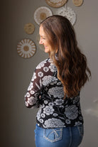 woman wearing a black white floral long sleeve mesh top and denim skirt for spring outfits