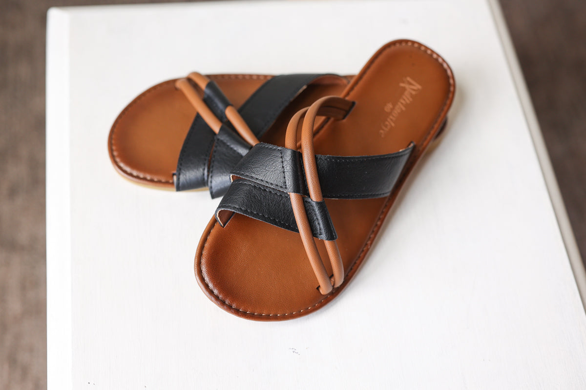 Brown sandal with black straps on a white surface