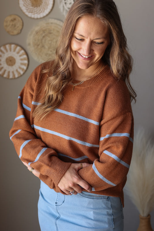 Camel blue stripe crewneck sweater styled for a cozy modest winter outfit, perfect for casual mom everyday wear with a decorative background