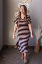 Woman wearing a striped dress standing in a room with decorative wall hangings.