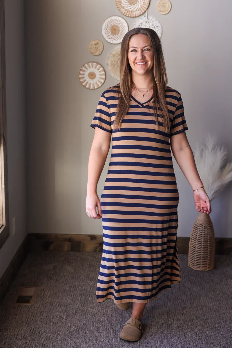 Woman wearing a striped dress standing in a room with decorative wall art.