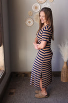 Woman wearing a striped dress standing in a room with decorative wall art.
