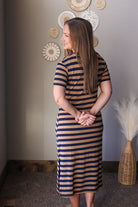 Woman wearing a striped dress standing in a room with decorative wall art.