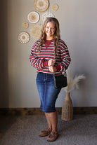 Full outfit view of a red striped long sleeve top with a denim midi skirt and brown boots.