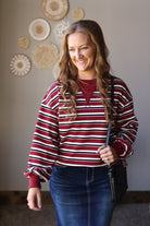 Front view of a red striped puff sleeve top with a round neckline, solid red cuffs, and a dark denim skirt.