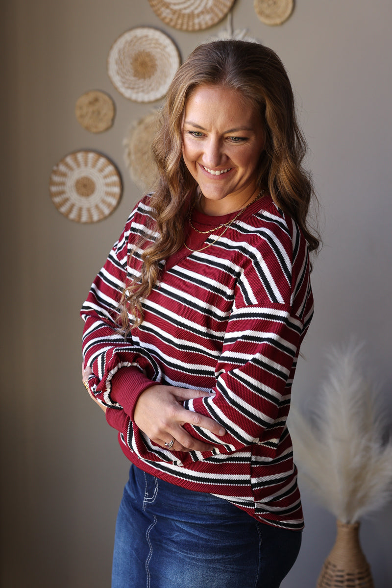 Side view of a red striped top showing its full puff sleeve, gathered red cuff, and denim skirt styling.