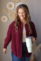 Close front view of an open wine corduroy shirt showing the collar, button placket, and chest pocket area.