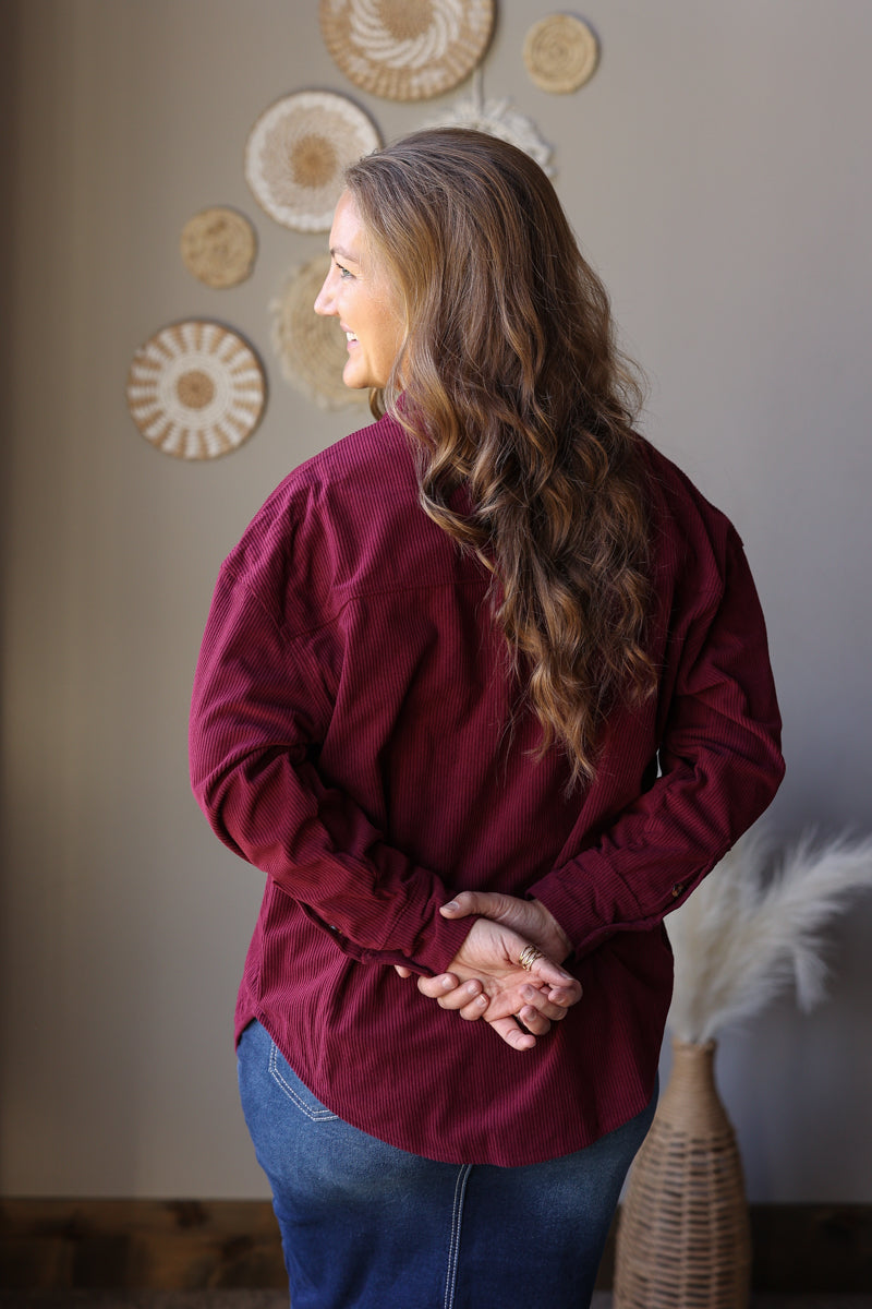 Back view of a wine corduroy long sleeve shirt showing the back yoke and curved hem.