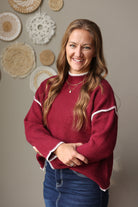 Front view of a cabernet knit sweater showing its mock neckline, ribbed cuffs, and contrast stitch details.