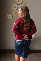 Back view of a cabernet stitch detail sweater styled with a dark denim midi skirt and brown boots.
