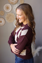 Side view of a brown sweater with a cream checkered front and solid sleeves.