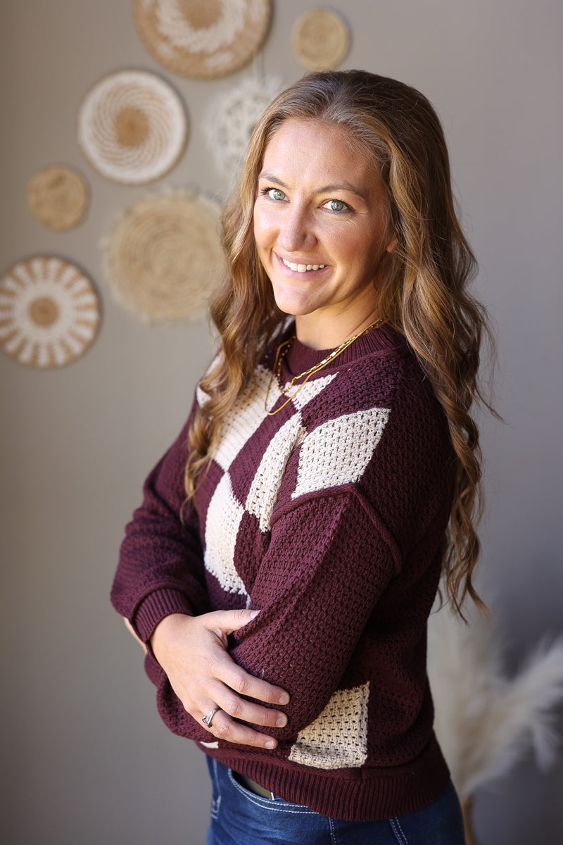 Three-quarter view of a brown and cream checkered front sweater with long solid sleeves.