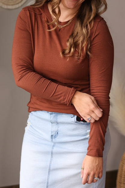 Person wearing a brown long-sleeve top and light blue denim skirt indoors for a cute fall winter top for women.